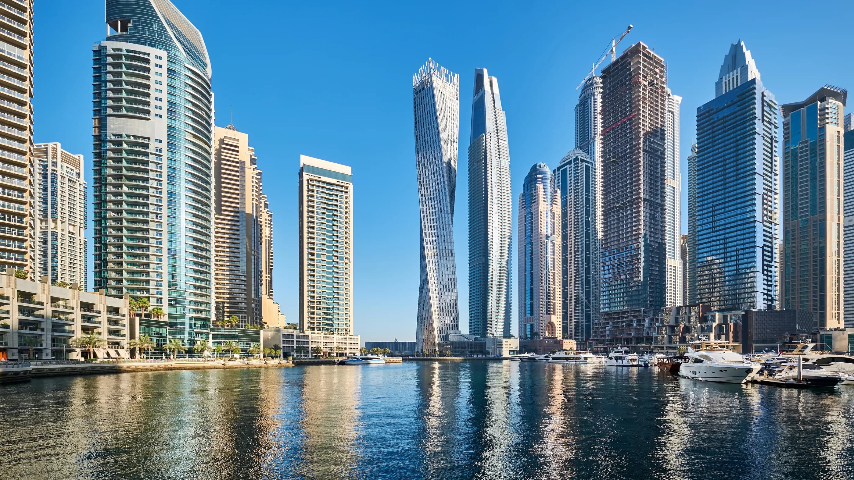 Residential towers along Dubai Marina reflected in the marina water on a clear day.